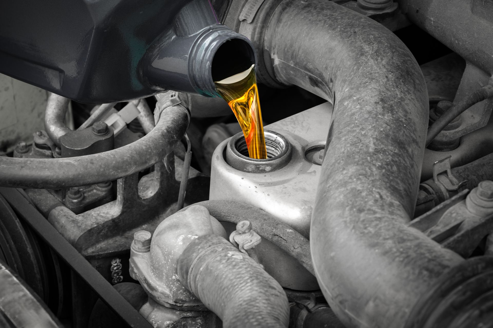 Mechanic kneeling beside a damaged vehicle, inspecting the engine with the hood open.