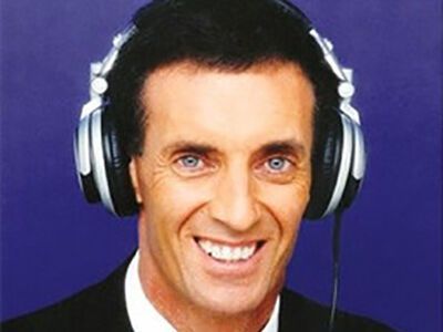 Smiling person wearing large silver headphones against a purple background