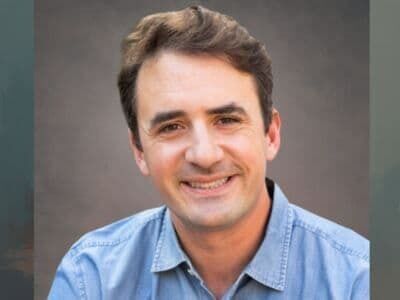 Smiling man in a light blue shirt against a gray background