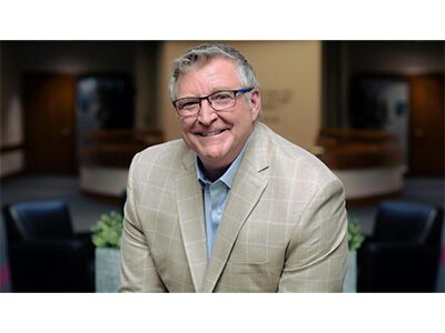 Smiling man in a beige blazer standing in an office lobby