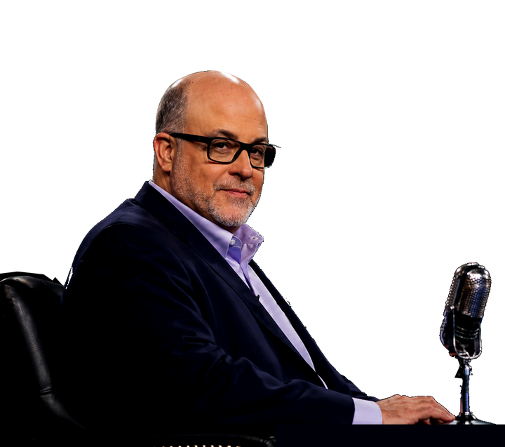 Man in a dark suit speaking into a microphone on a white background, lit with red and blue lighting