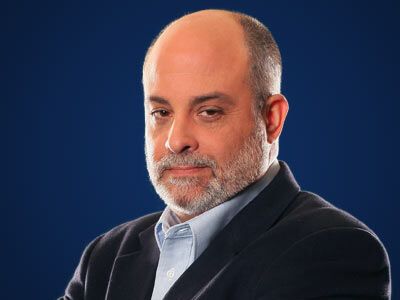 Portrait of a bald man with a gray beard in a dark blazer against a blue background