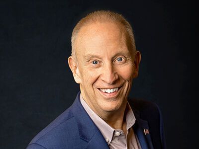 Smiling man in a blue suit against a dark background