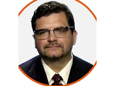 Man in glasses and suit with striped tie, framed by an orange circular border
