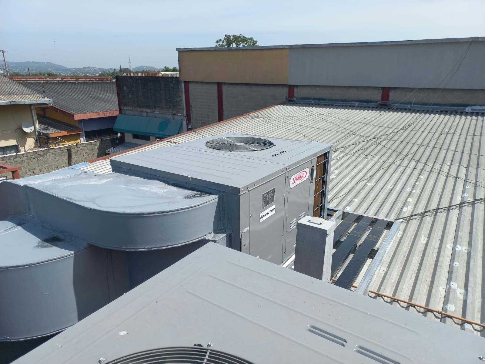 Unidades de climatización en la azotea de un techo de chapa ondulada bajo un cielo despejado.