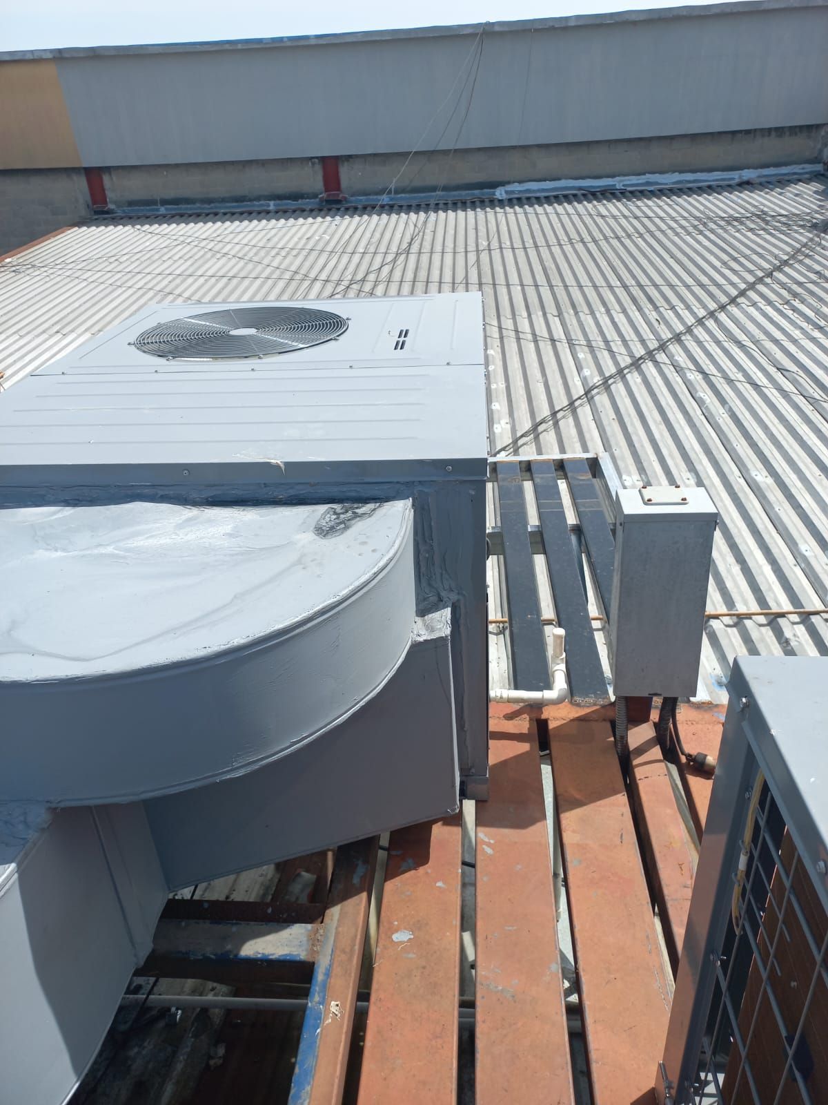 Unidades de climatización y conductos exteriores instalados en la azotea, sobre una plataforma metálica con barandillas.