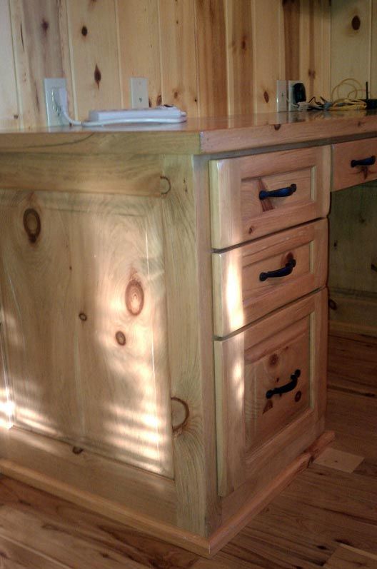 a wooden desk with drawers and cabinets in a room with wooden walls .