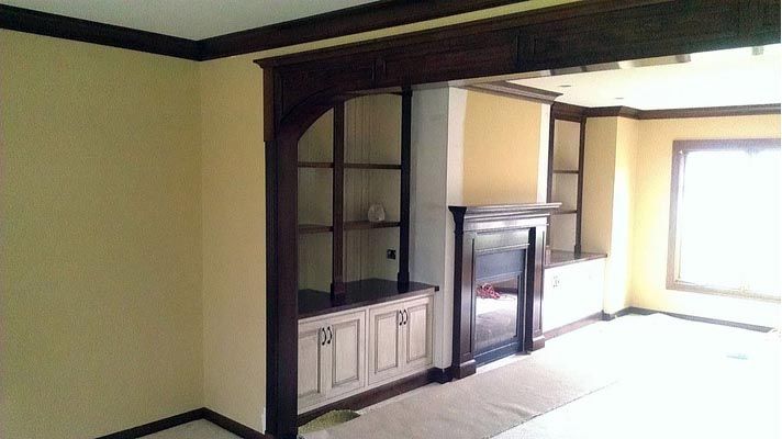an empty living room with a fireplace and shelves