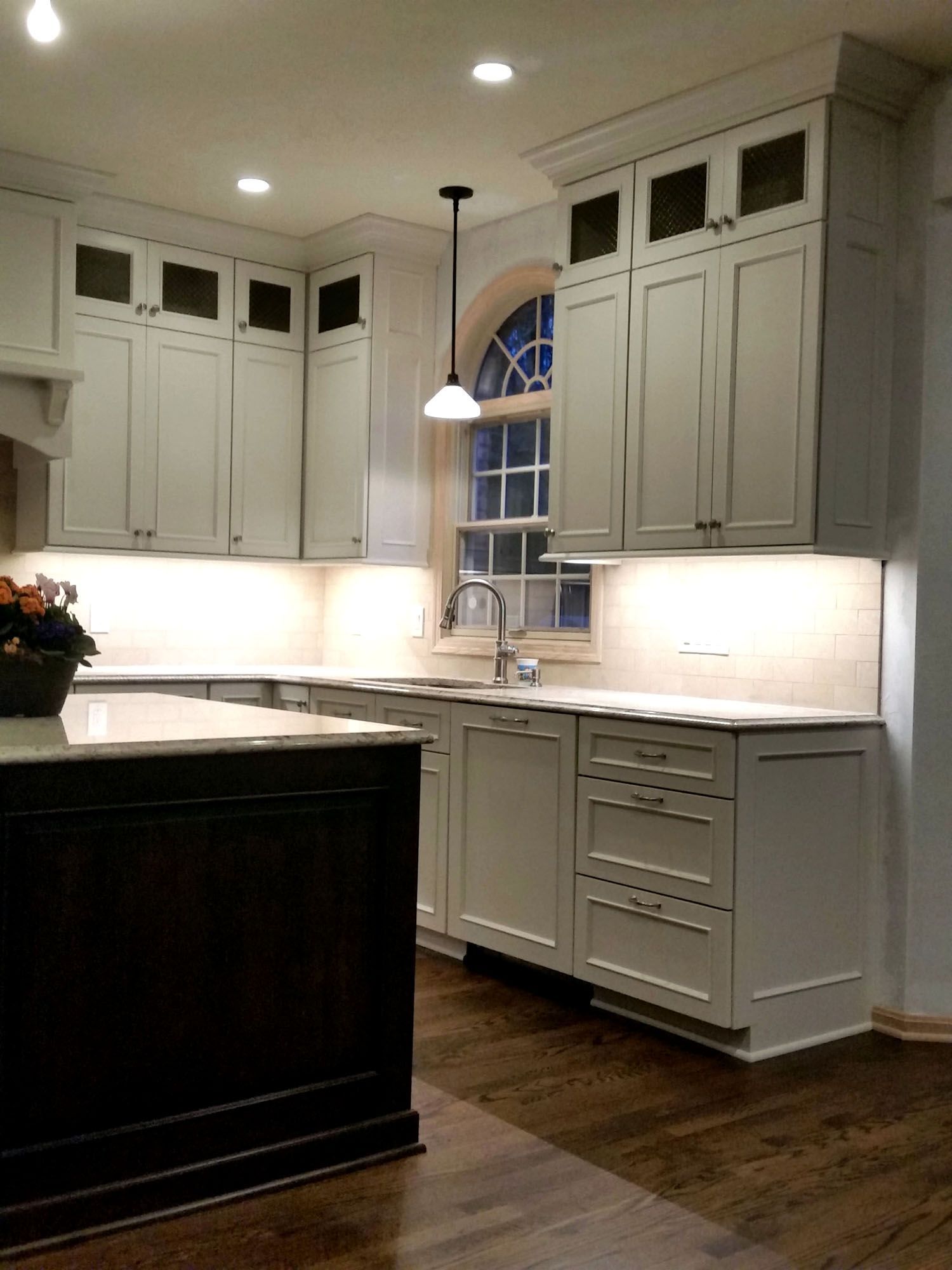 a kitchen with white cabinets and a black island
