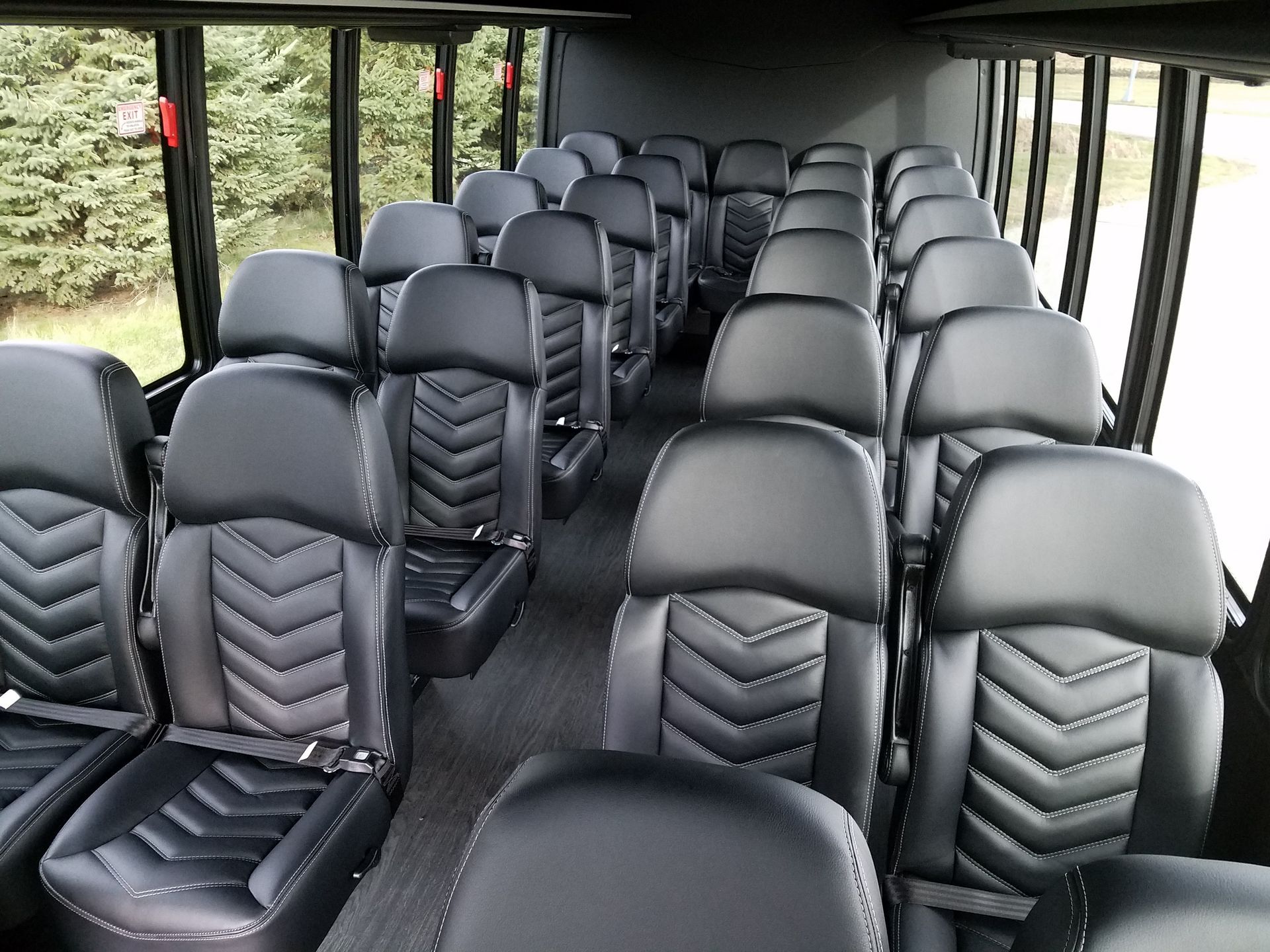 Interior of a bus with rows of black leather seats and windows along the sides.