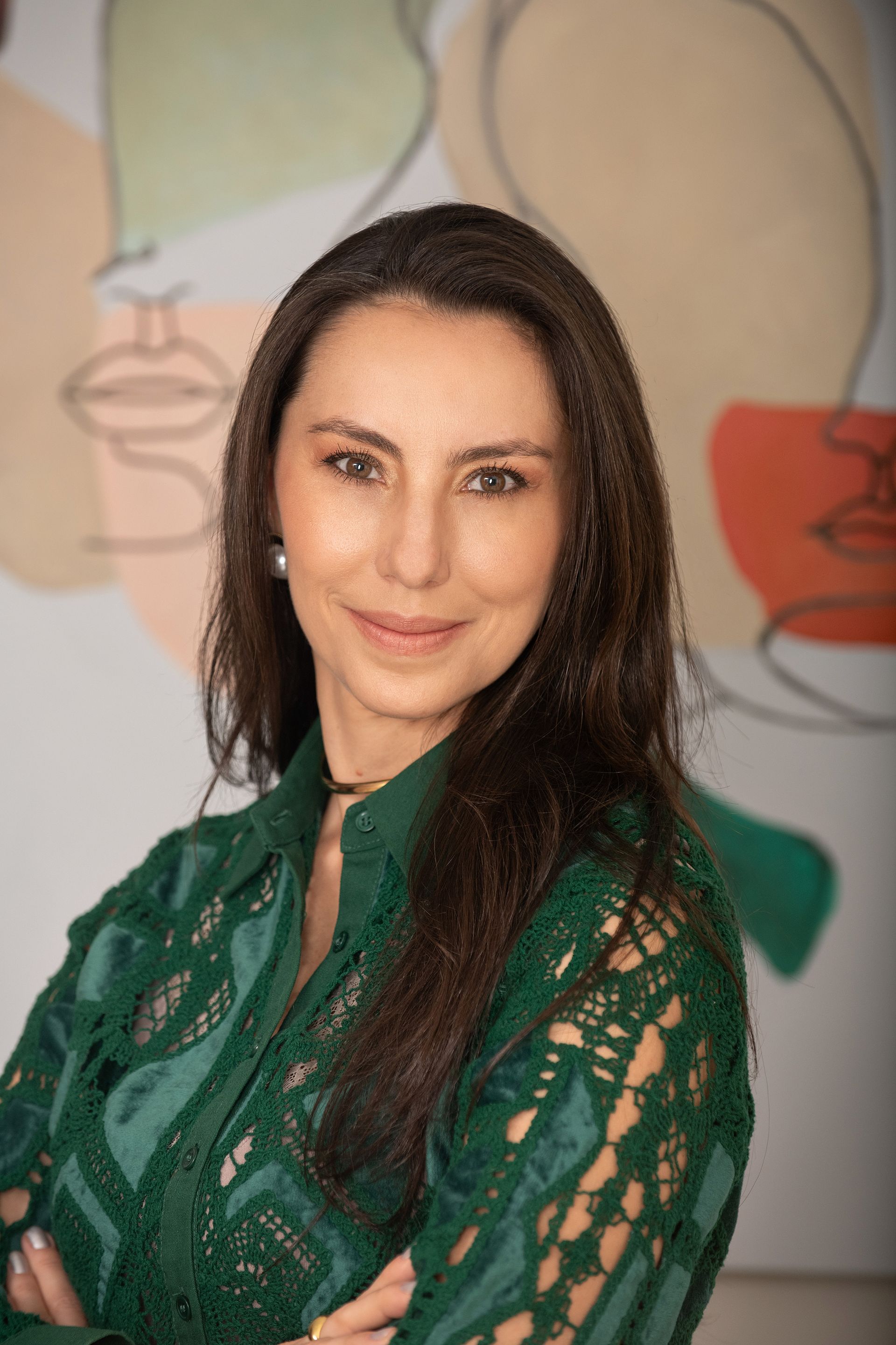 Uma mulher de camisa verde posa para uma foto com os braços cruzados.