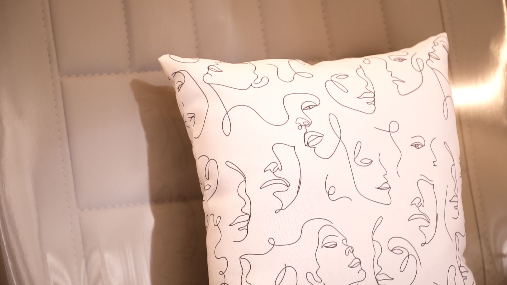 Um travesseiro branco com rostos está sobre uma cama.