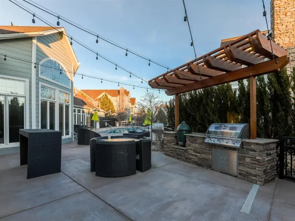 Outdoor grilling area with a built-in grill and seating near a pool.