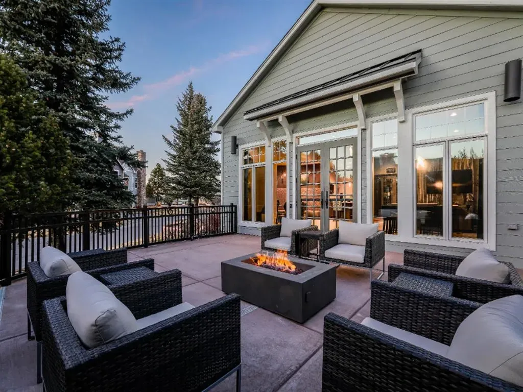 Outdoor patio seating area with a fire pit and lounge chairs, next to a building.