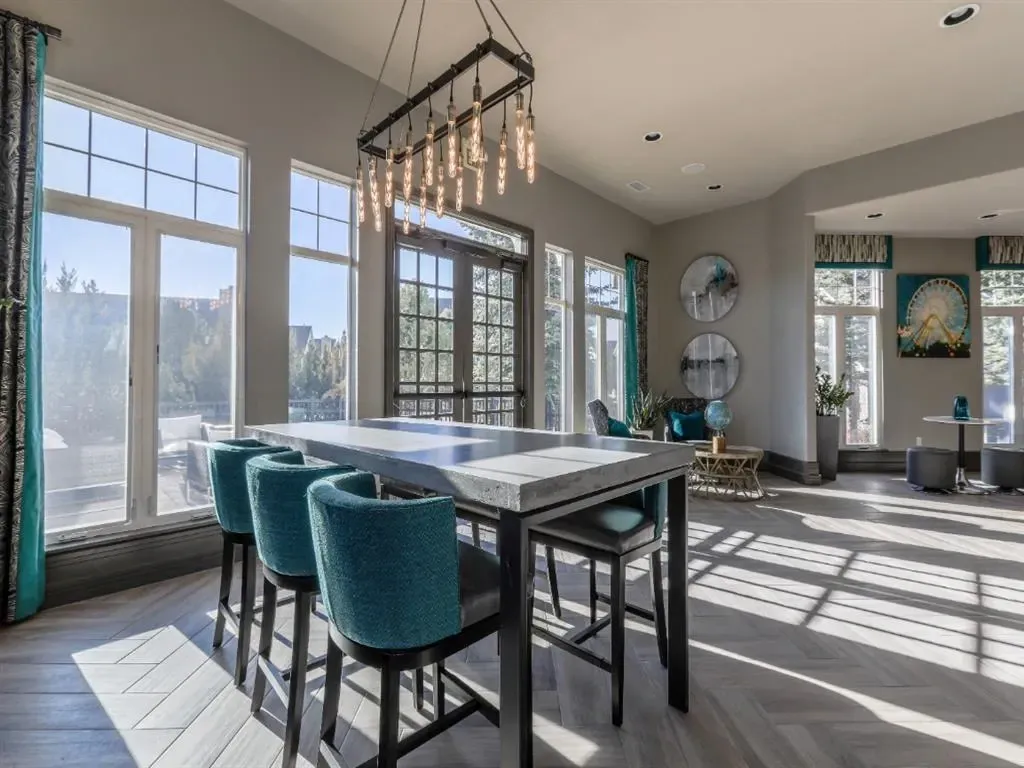 Communal dining table with high chairs in a bright, modern lounge area with large windows.
