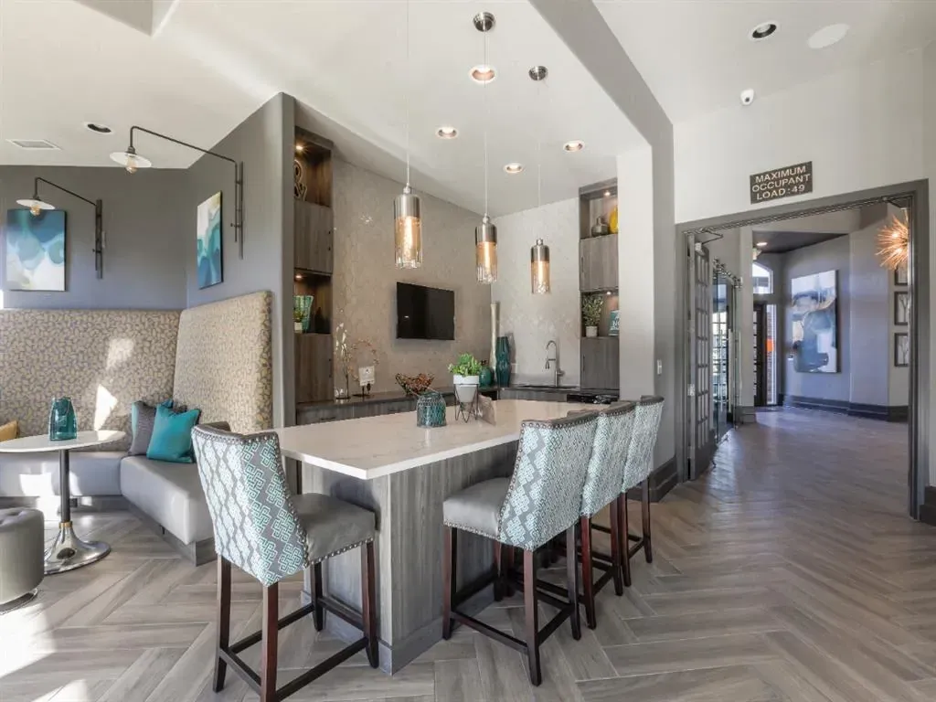 Modern kitchen island with bar stools and seating area in apartment community