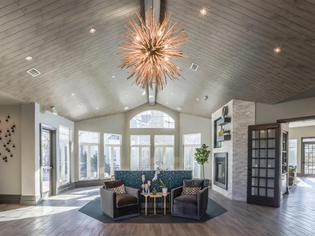 Spacious, sun-drenched community lounge area with a modern fireplace and comfortable seating.