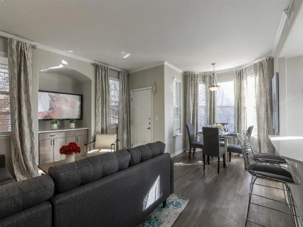 Spacious living and dining area with modern furniture, large windows, and a TV.