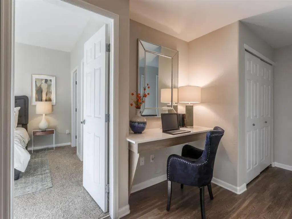 Desk area with a laptop, chair, and mirror.