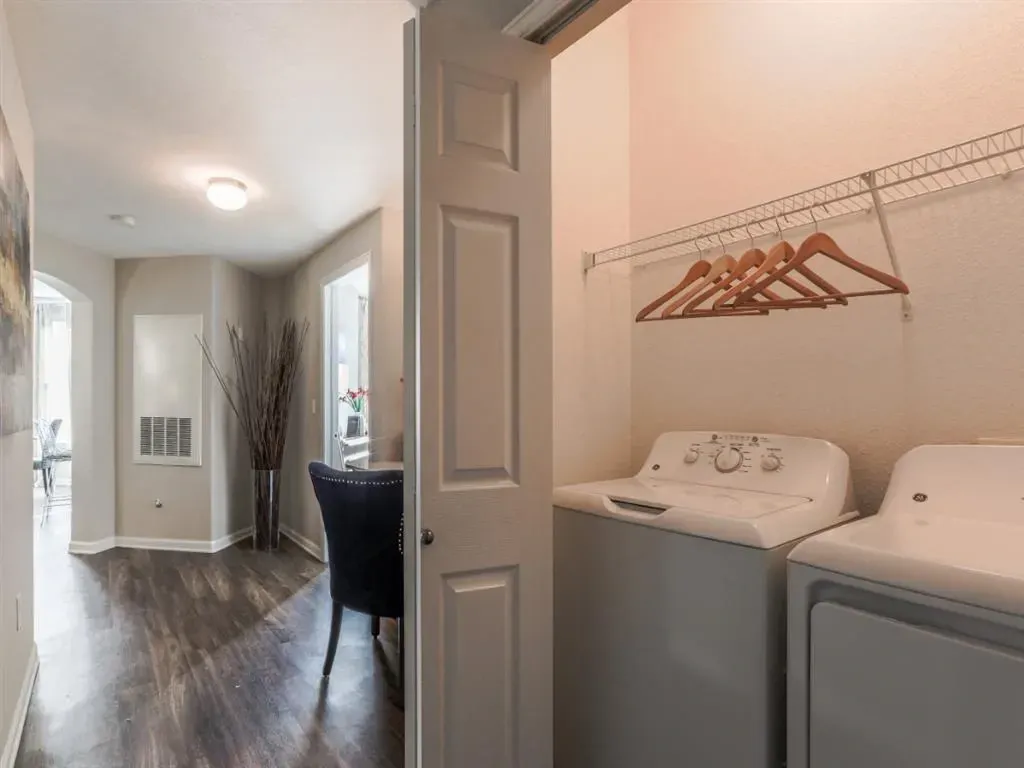 Interior laundry room with stacked washer and dryer and hanging rack