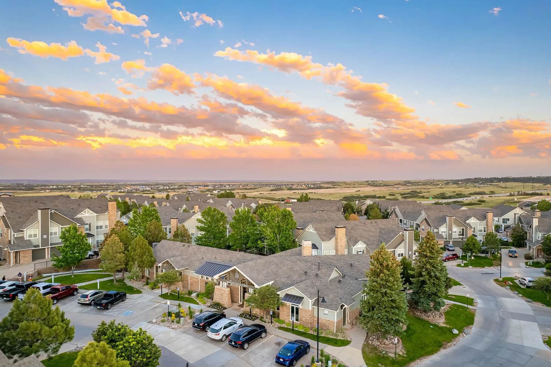 Apartment complex buildings and parking lot during sunset.
