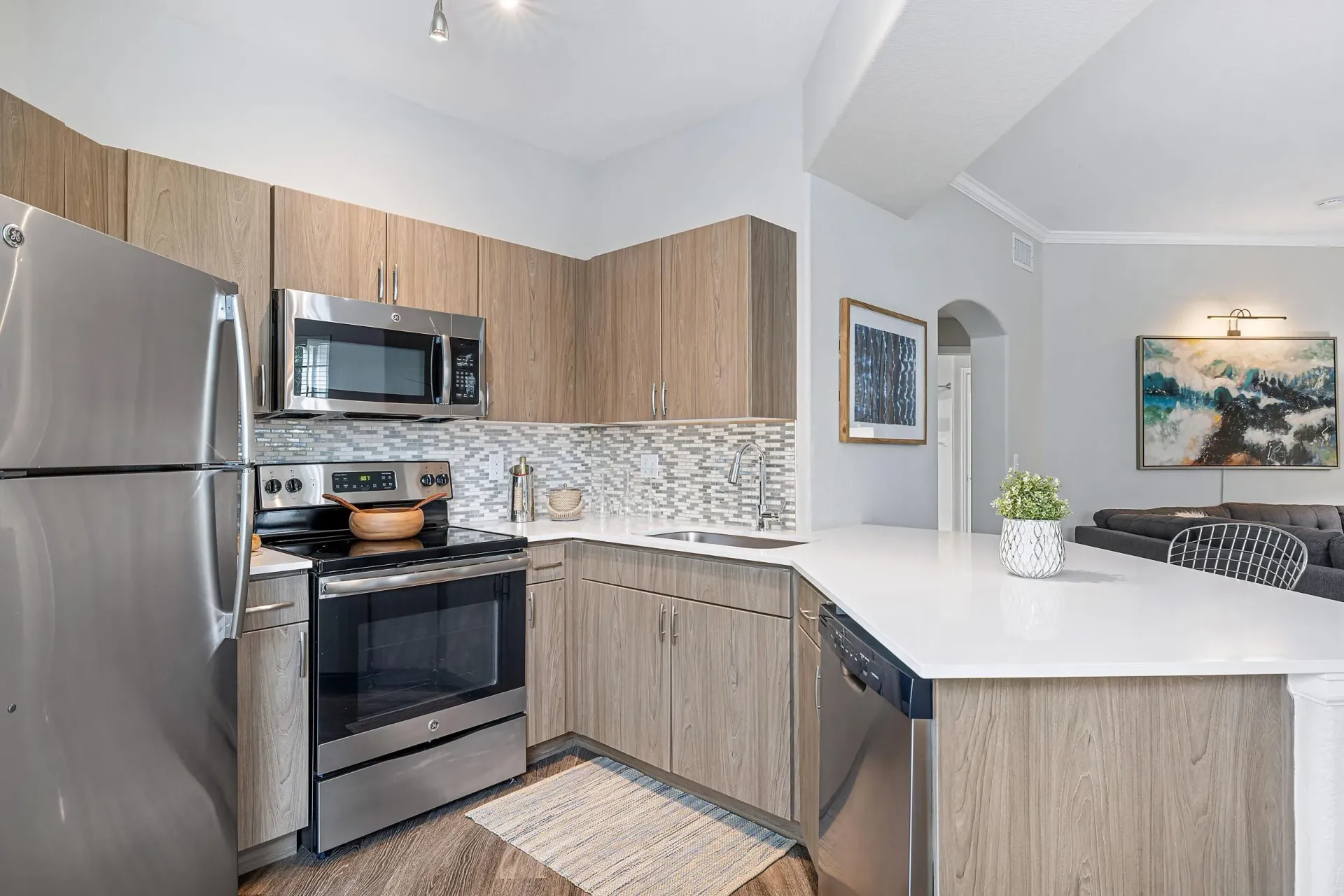 Modern apartment kitchen with stainless steel appliances, wood cabinetry, and quartz countertops.