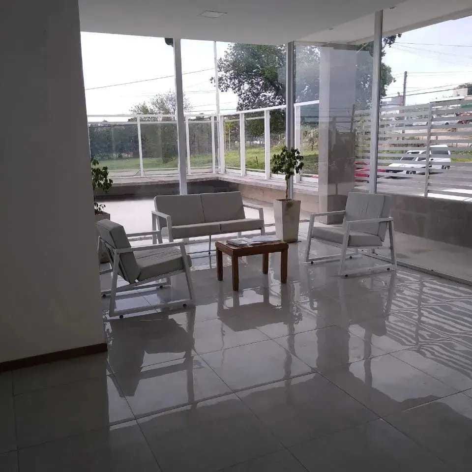 Entrada moderna al edificio con escalones, puertas de cristal y paredes laterales con listones blancos.