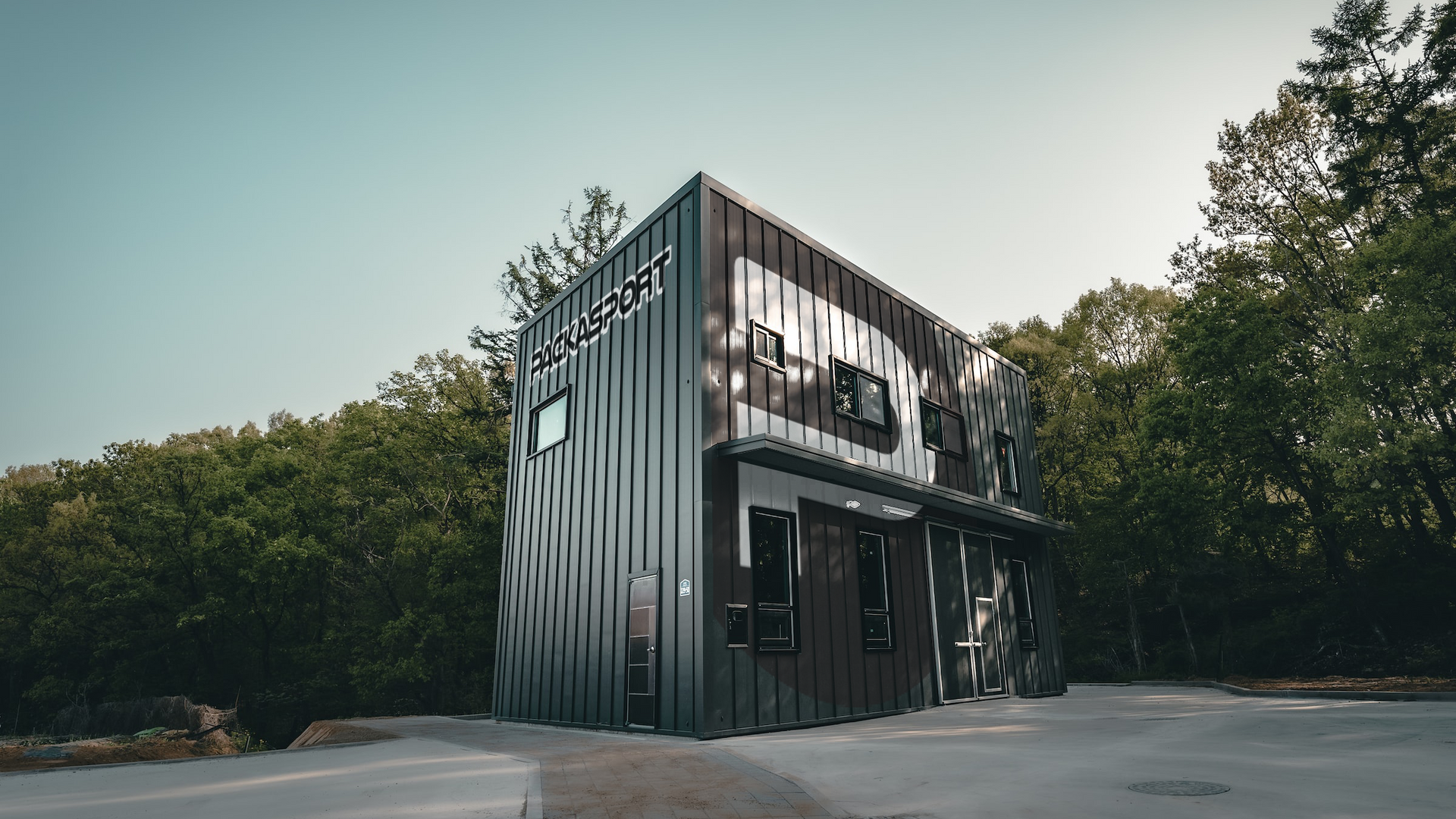 A large black building is sitting in the middle of a forest.