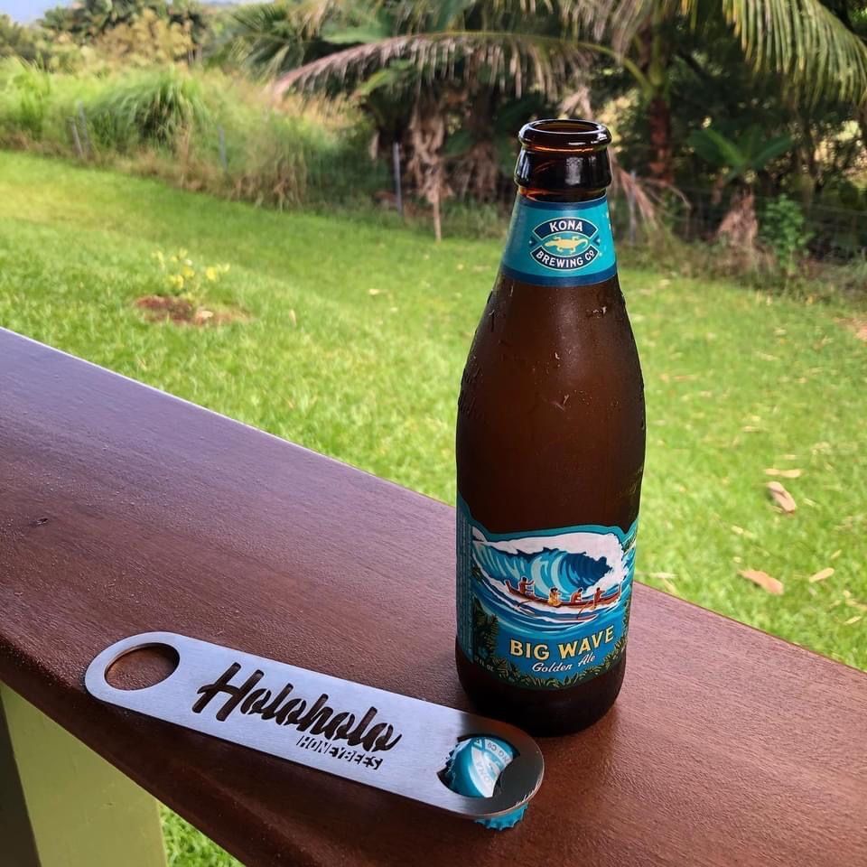 A bottle of big wave beer next to a bottle opener