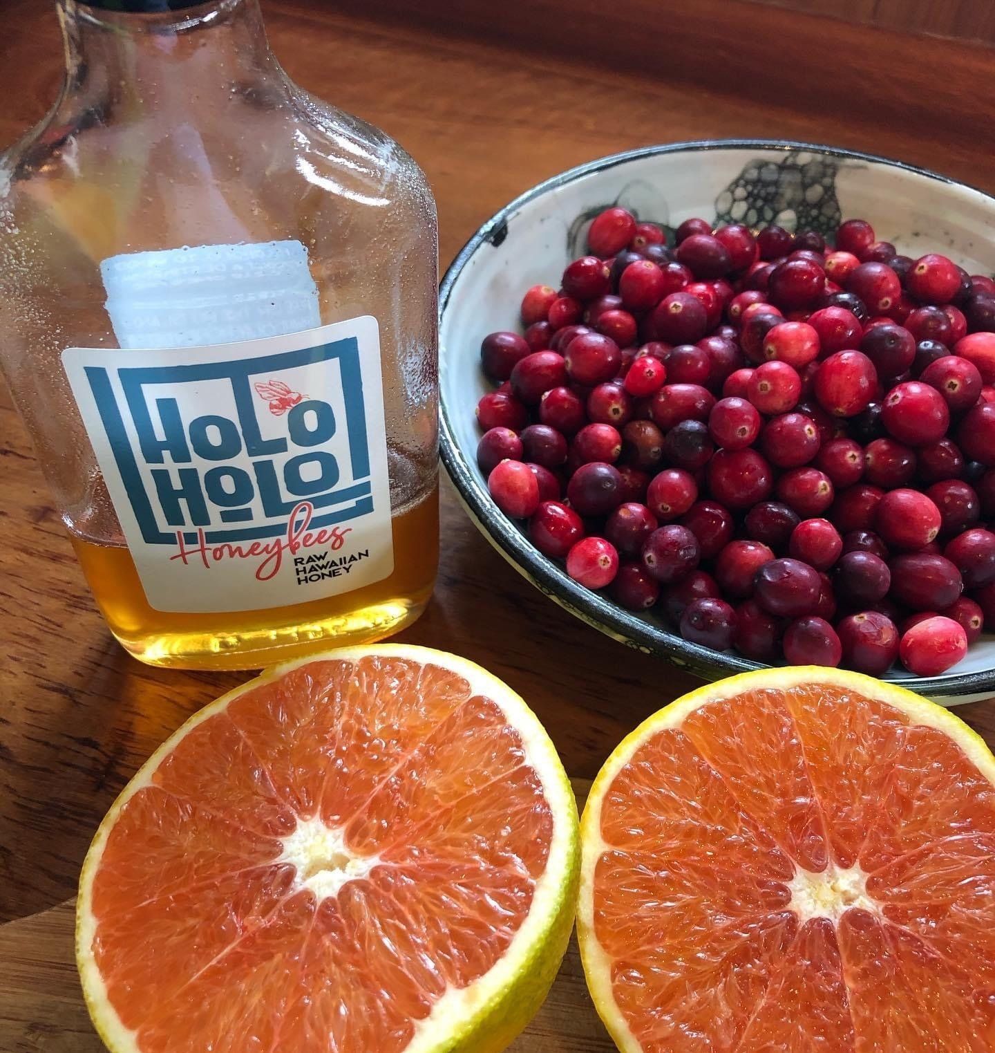 A bottle of holo holo next to a bowl of cranberries