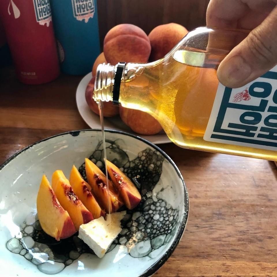 A person pouring liquid into a bowl of sliced peaches