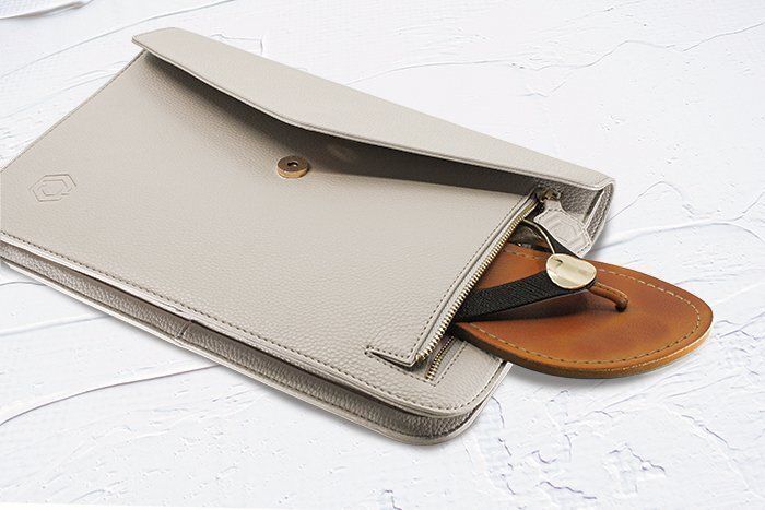 A white purse with a pair of flip flops inside of it.