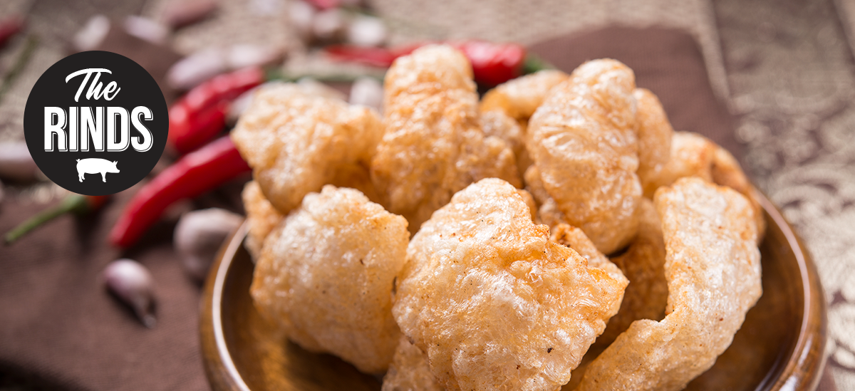 A bowl of pork rinds is sitting on a table.