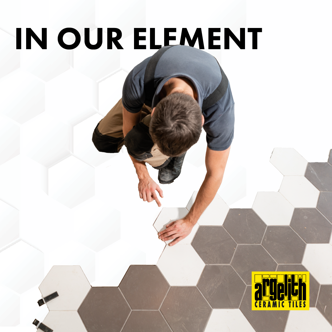 A worker installs white and gray hexagonal tiles on a floor, with 