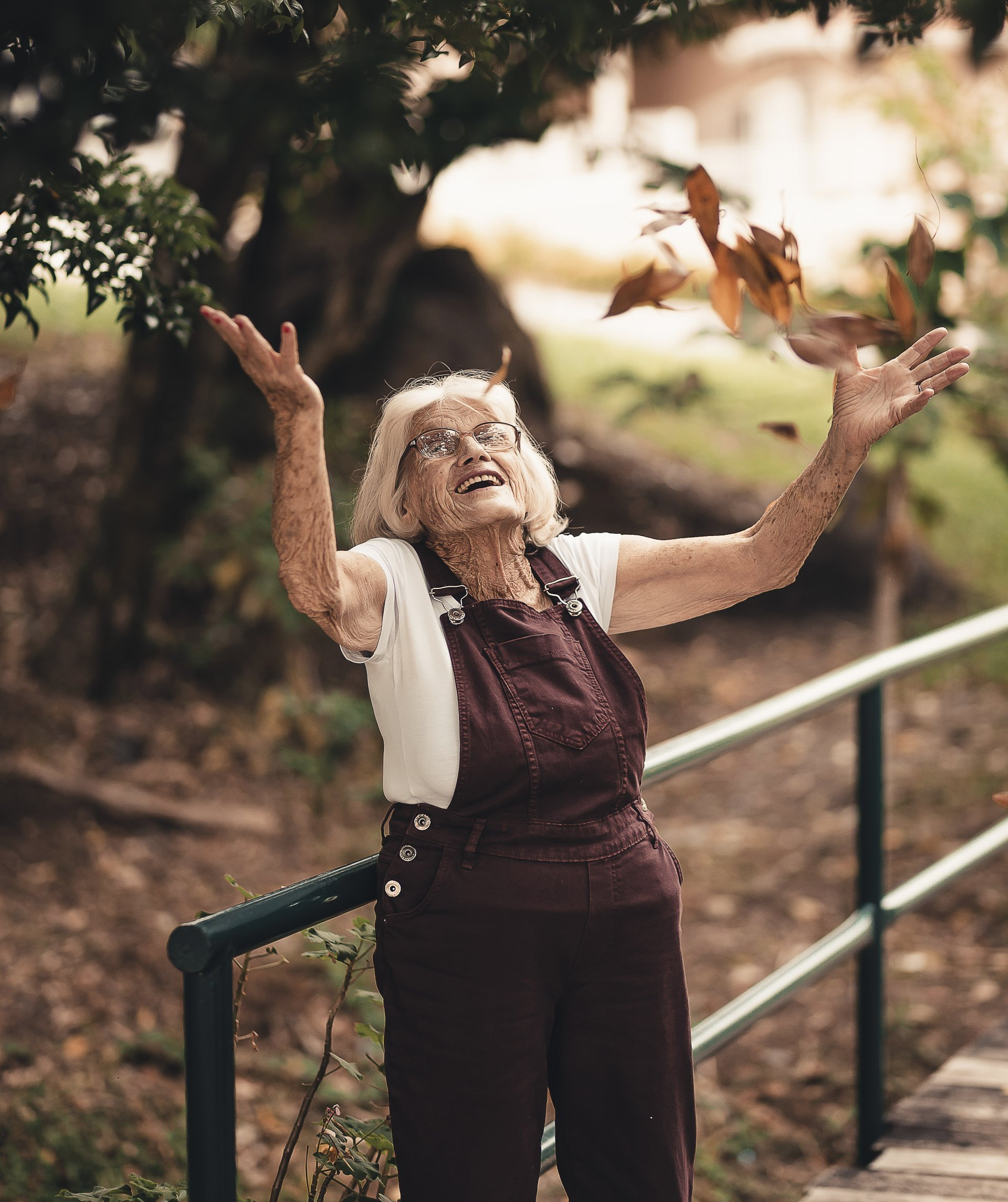Joyful elderly woman throwing leaves in the air.