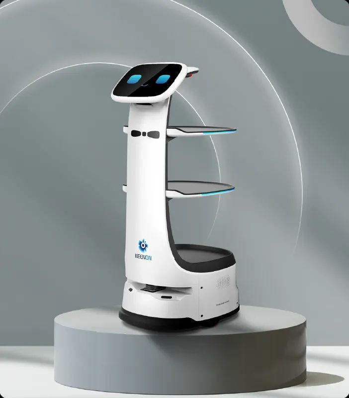 White service robot with shelves, blue accents, on a grey pedestal against a grey backdrop.
