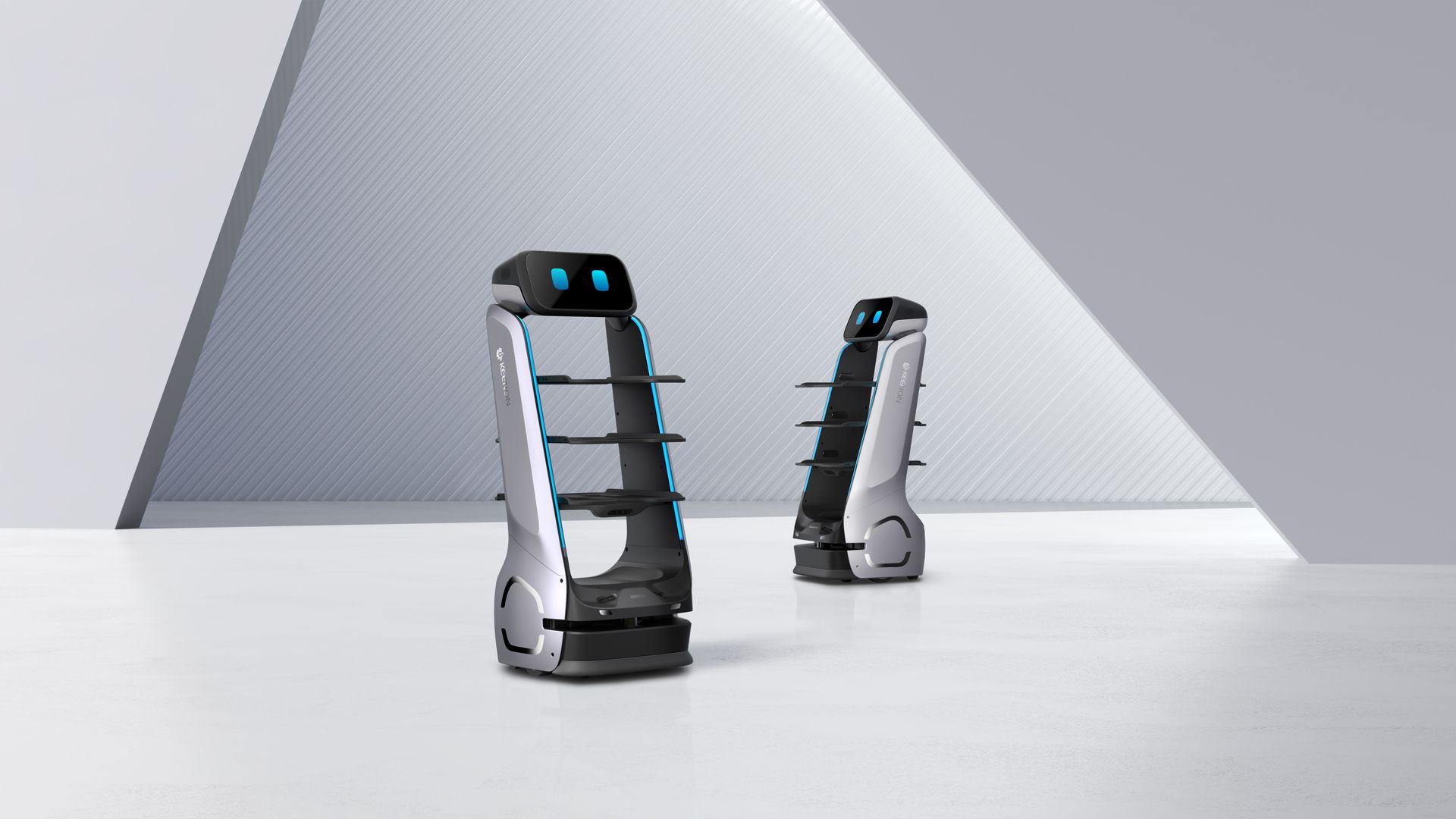Two sleek, silver autonomous delivery robots with black shelves and digital faces stand in a minimalist white room.