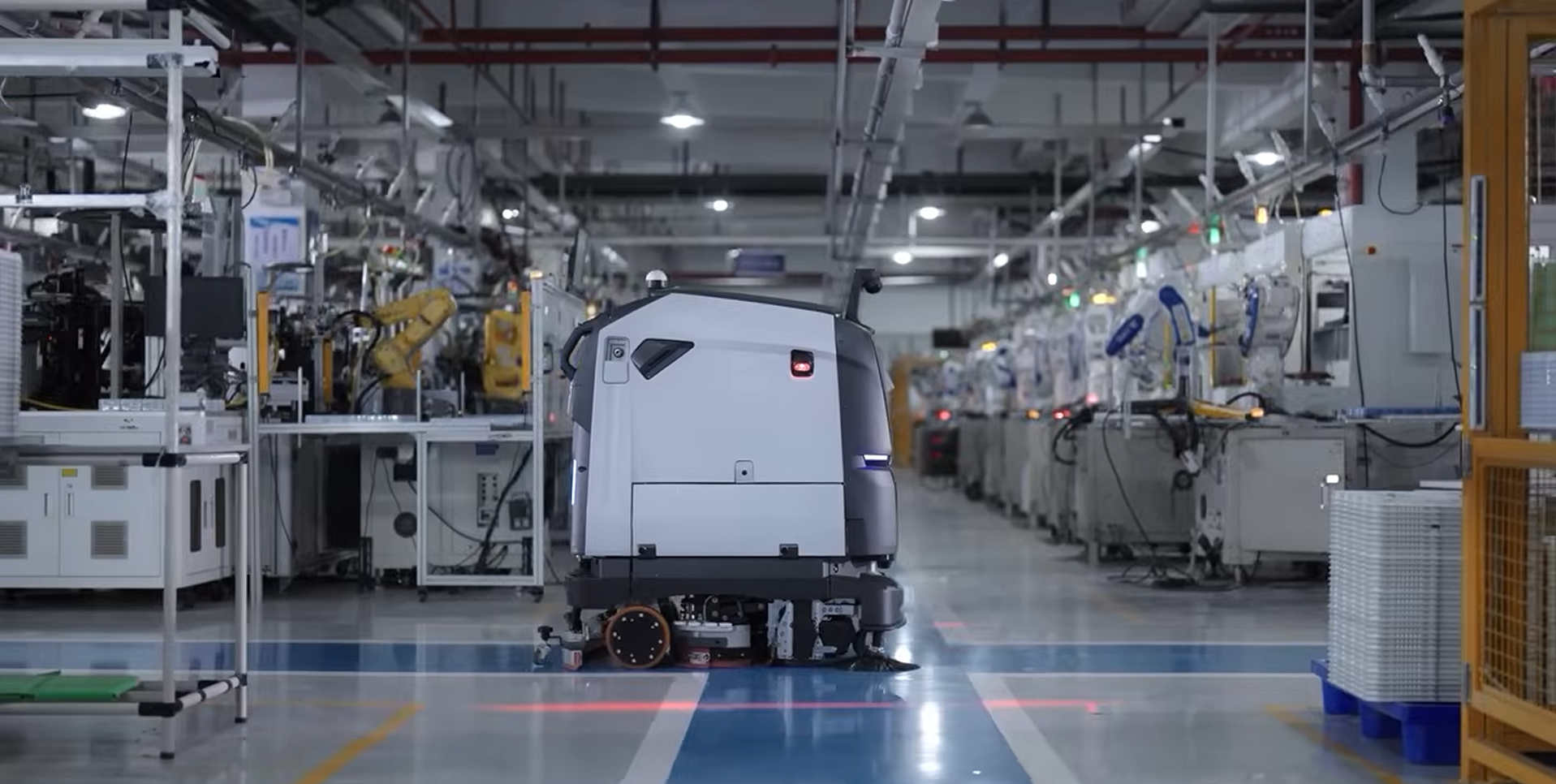 Automated factory assembly line with a white robot or vehicle centered in a large industrial hall