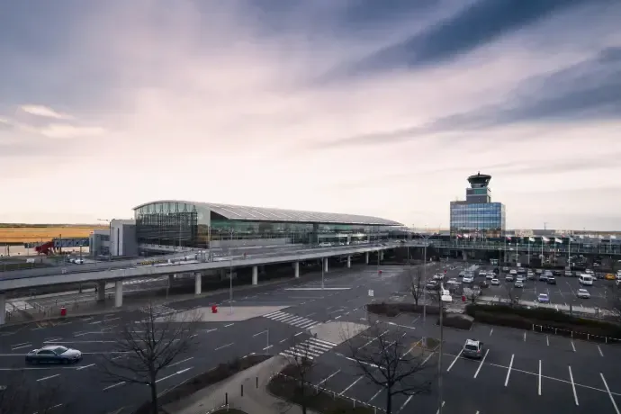 Airport terminal and parking lot under a cloudy sky at dusk