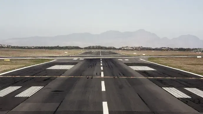 Runway stretching into a hazy landscape with mountains in the distance.