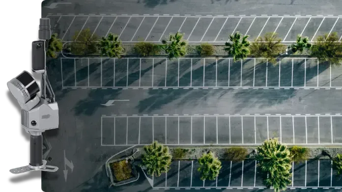 Aerial view of a nearly empty parking lot with trees and a security camera mounted at the edge.
