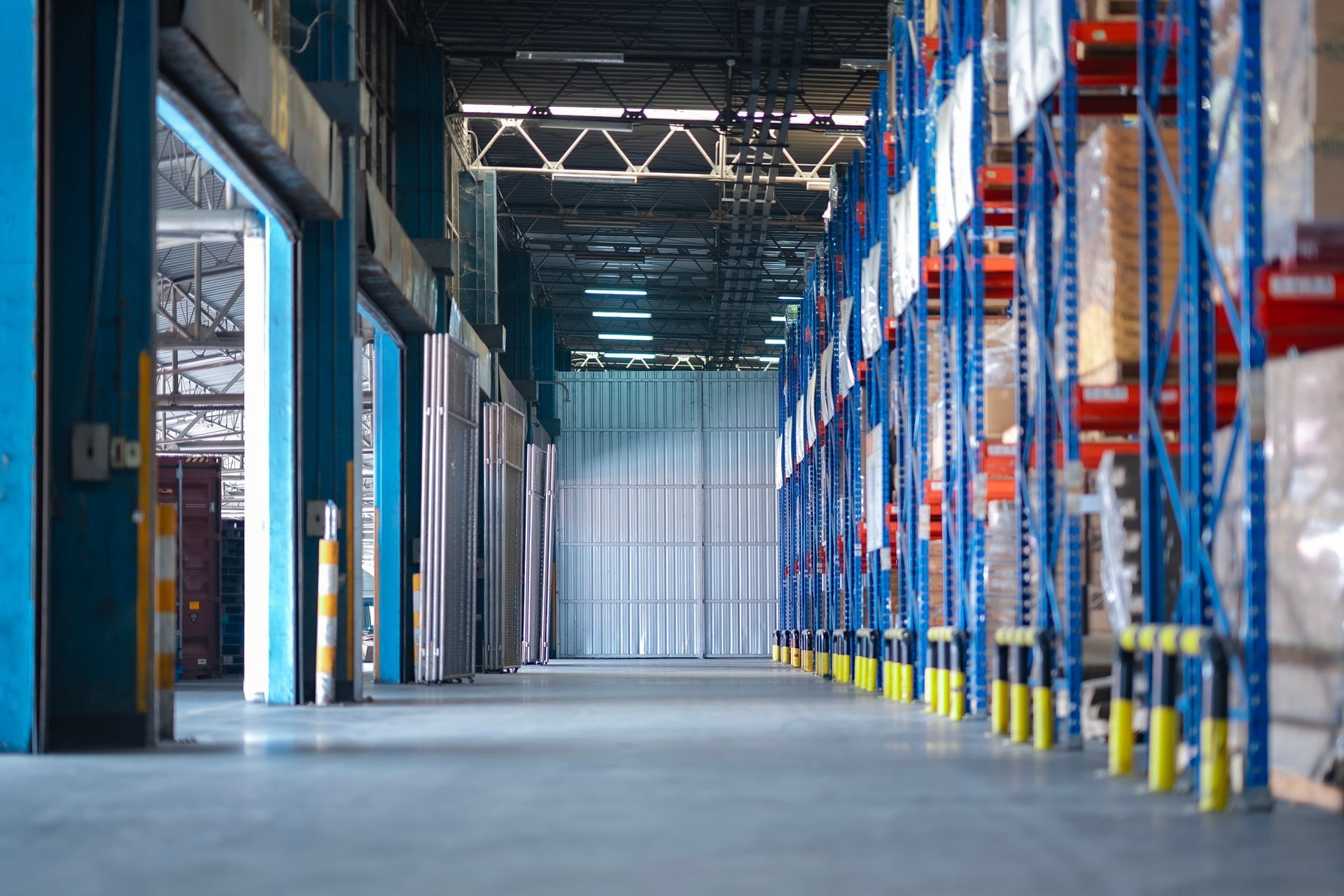 Empty warehouse aisle with blue-and-orange storage racks and tall ceiling lights