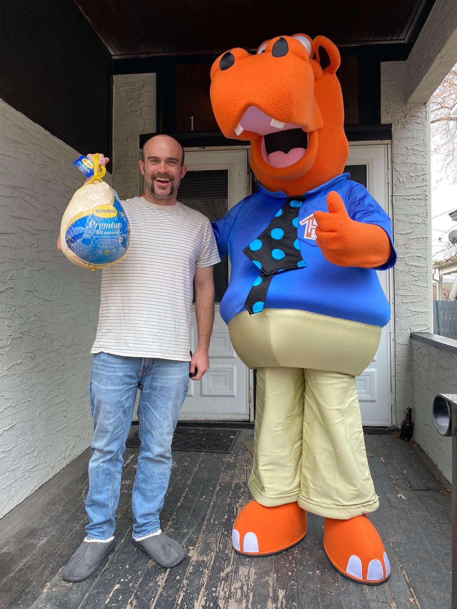 Housing Hub Mascot, Hubbs with tenant holding frozen turkey.