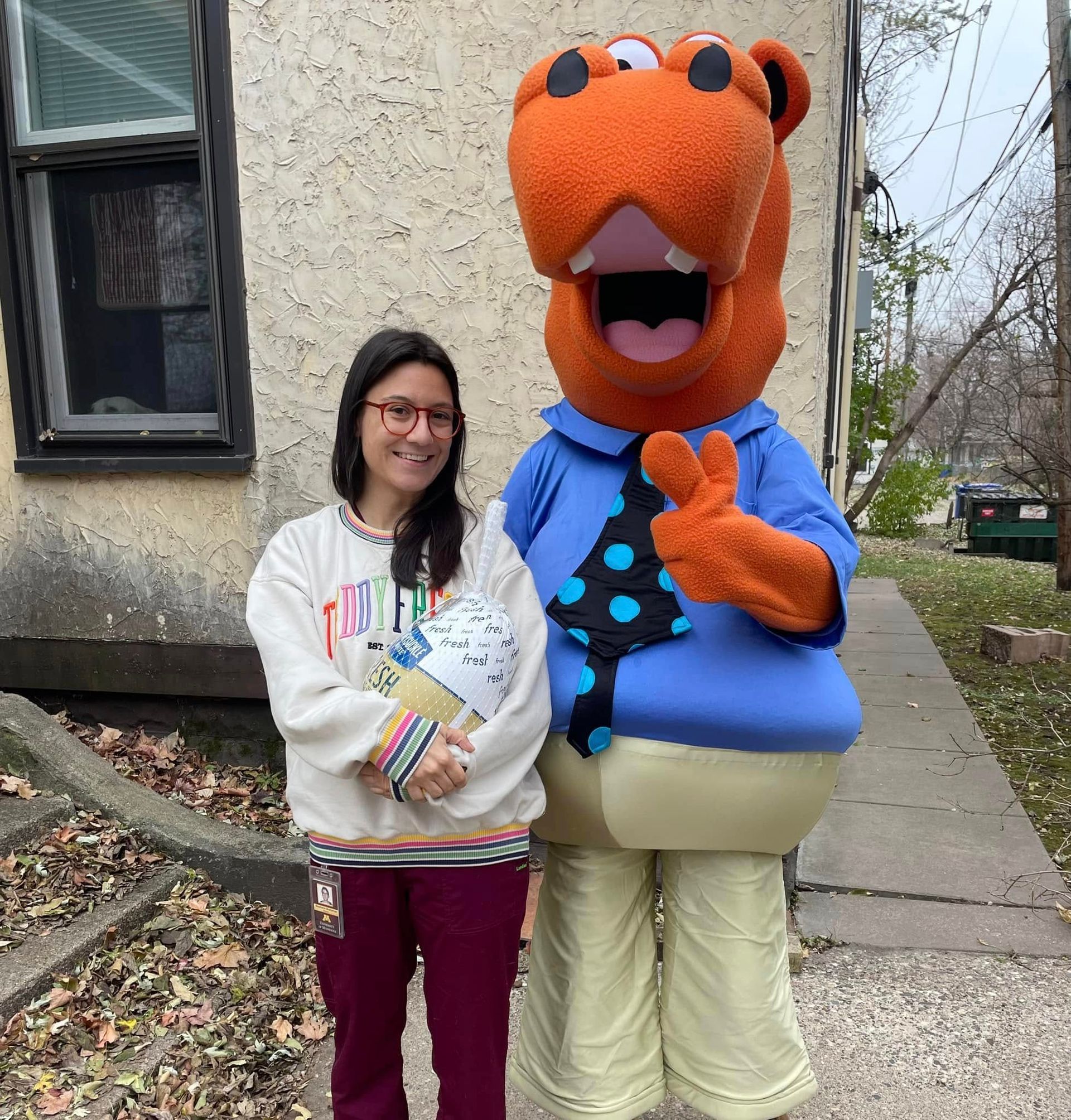Housing Hub Mascot, Hubbs with tenant holding frozen turkey.