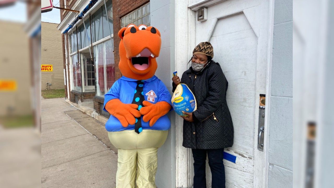 Housing Hub Mascot, Hubbs with tenant holding frozen turkey.