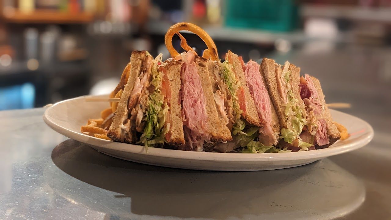 A club sandwich is sitting on a white plate on a table.
