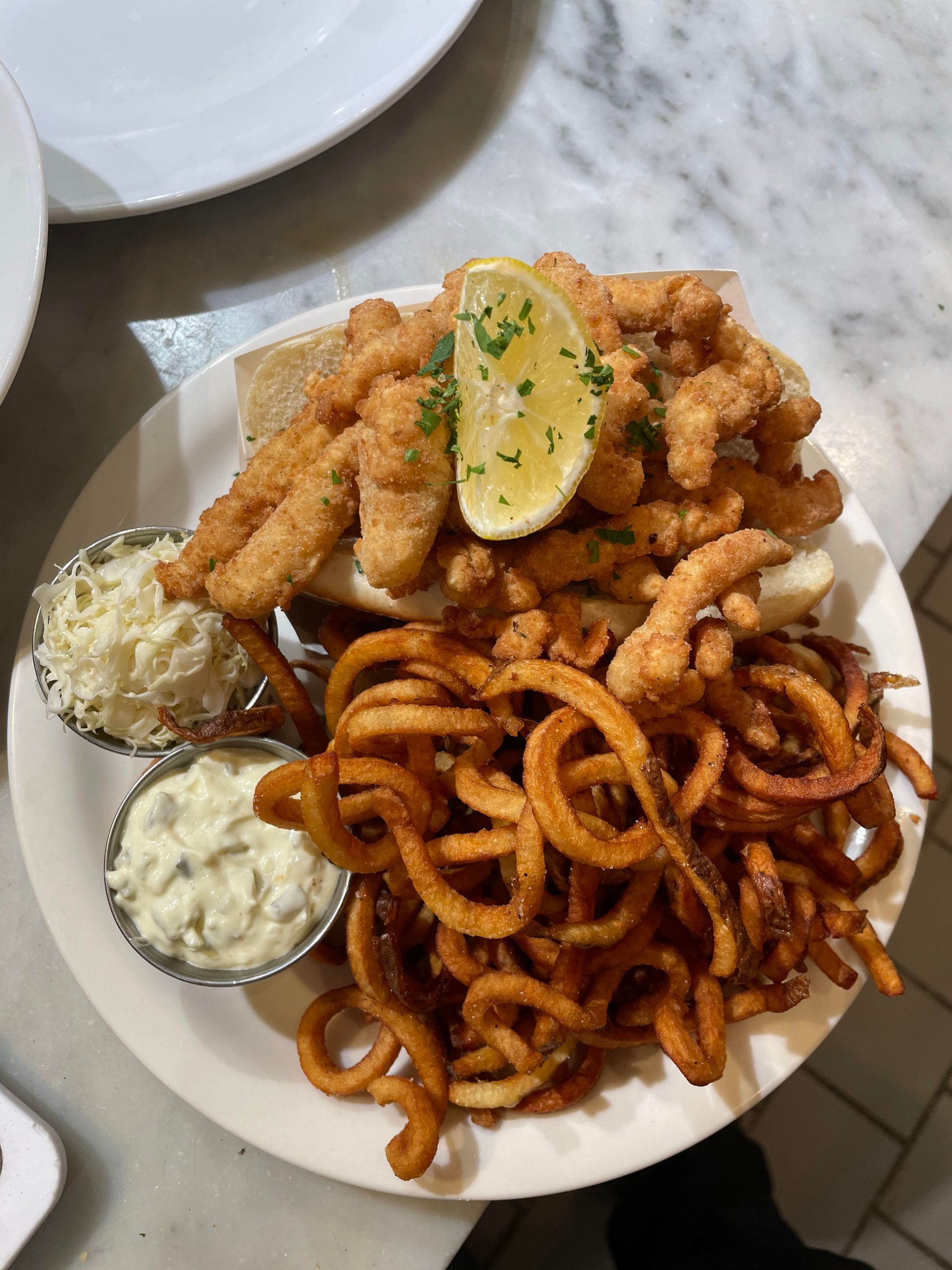 A plate of food with curly fries and bread on a table.