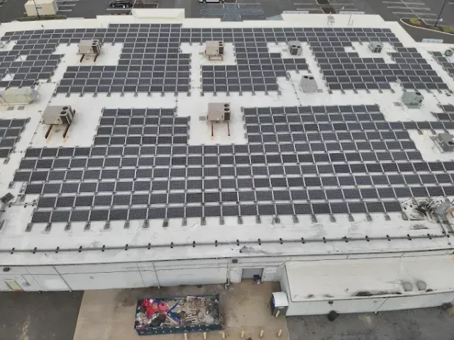 Rooftop with rows of solar panels and HVAC units, viewed from above