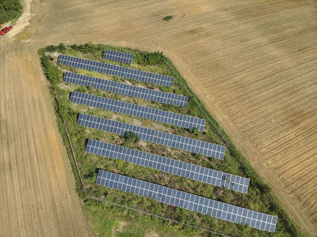 Two workers cleaning solar panels on a rooftop, spraying water under a blue sky.