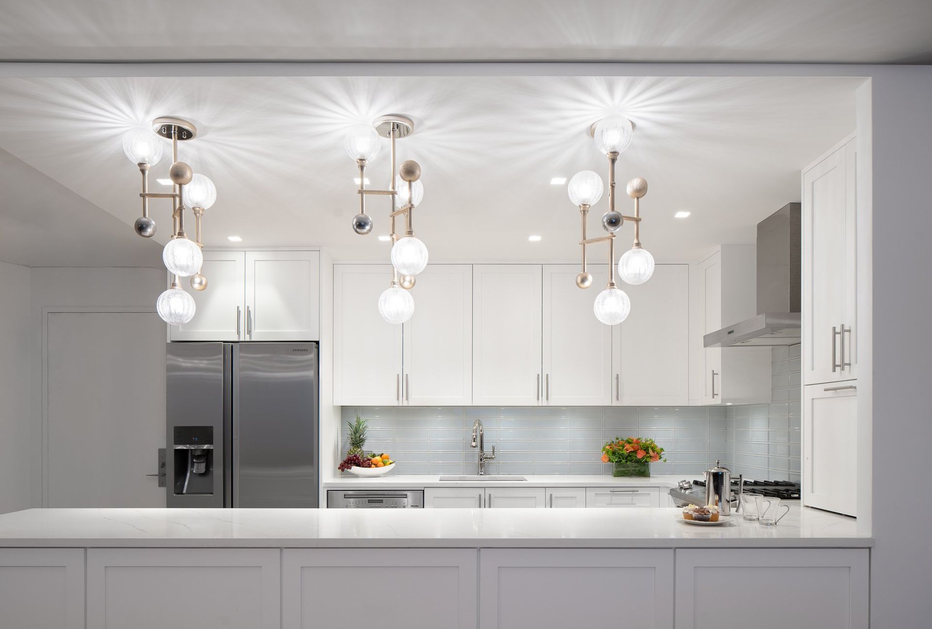 Bright white kitchen with island, pendant lights, stainless appliances, and clean modern finishes